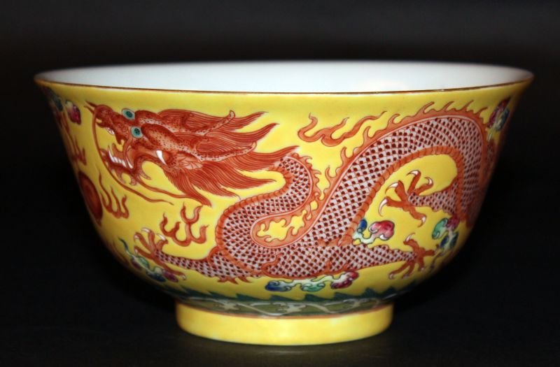 A GOOD QUALITY CHINESE YELLOW-GROUND PORCELAIN DRAGON: A GOOD QUALITY CHINESE YELLOW-GROUND PORCELAIN DRAGON BOWL, the sides painted with two dragons pursuing a flaming pearl above waves, the base with a six-character Guangxu mark, 6.3in diameter & 3.25in