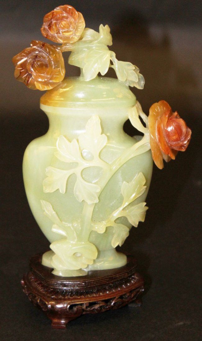 A 20TH CENTURY CHINESE JADE-LIKE BOWENITE VASE & COVER,: A 20TH CENTURY CHINESE JADE-LIKE BOWENITE VASE & COVER, with fitted wood stand and box, the vase and cover carved with foliage in high relief, the vase & cover 6.75in high overall. £100-150.