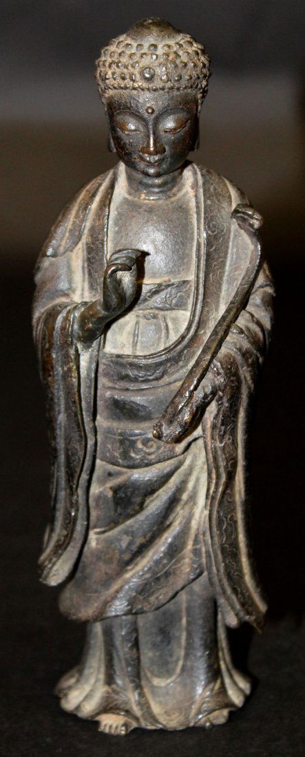 A GOOD 16TH CENTURY CHINESE BRONZE FIGURE OF BUDDHA,: A GOOD 16TH CENTURY CHINESE BRONZE FIGURE OF BUDDHA, standing with a benign expression and holding a ruyi sceptre in one hand, the hems of his flowing robes engraved, the whole with good unpolished pa