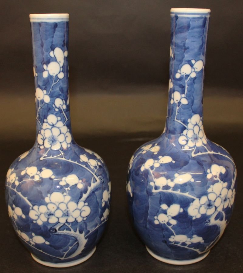 A PAIR OF 19TH CENTURY CHINESE BLUE & WHITE PORCELAIN: A PAIR OF 19TH CENTURY CHINESE BLUE & WHITE PORCELAIN BOTTLE VASES, the sides of each painted with prunus blossom reserved in white against a blue-wash crackled-ice ground, 10.25in high. £100-150.