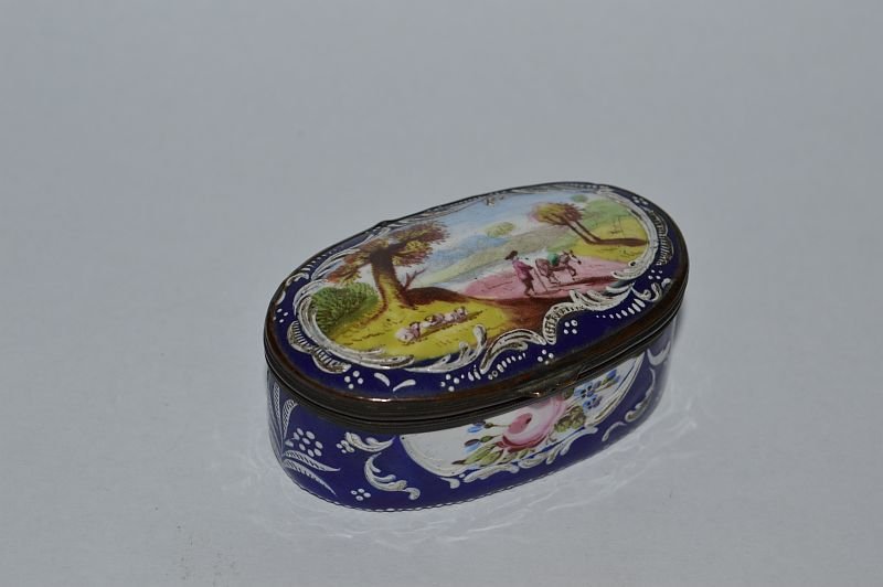 A BILSTON ENAMEL OVAL SNUFF BOX AND COVER, blue ground,: A BILSTON ENAMEL OVAL SNUFF BOX AND COVER, blue ground, the lid with a landscape scene, man with horse.2.5ins. £100-150.