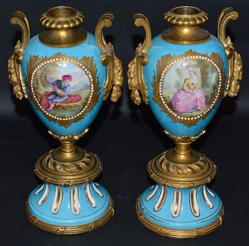 A GOOD PAIR OF 19TH CENTURY FRENCH SEVRES PORCELAIN TWO: A GOOD PAIR OF 19TH CENTURY FRENCH SEVRES PORCELAIN TWO HANDLED URNS, pale blue ground painted with reverse oval panels, young lady and a young man playing a mandolin, flowers to the reverse, with ric