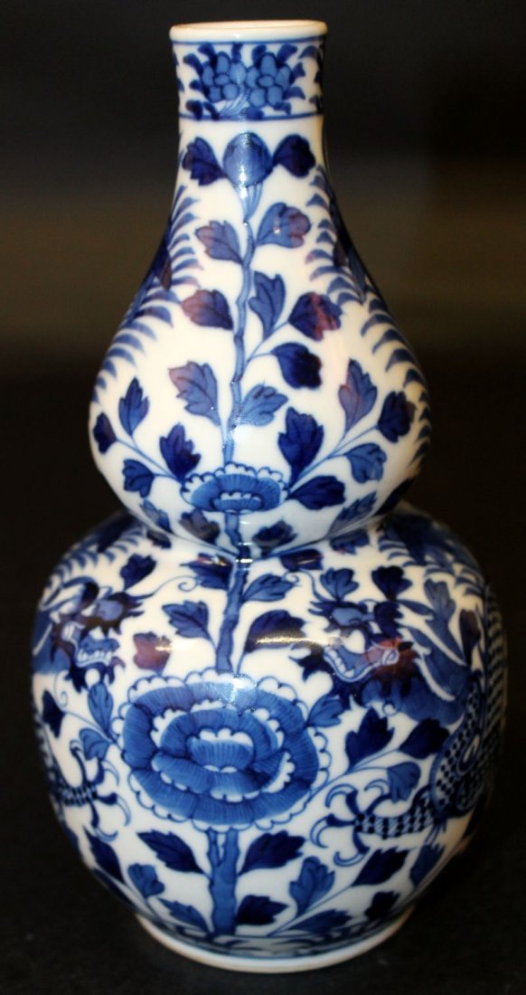 A 19TH CENTURY CHINESE BLUE & WHITE PORCELAIN: A 19TH CENTURY CHINESE BLUE & WHITE PORCELAIN DOUBLE-GOURD DRAGON VASE, the sides painted with two confronting dragons amidst leaf-stemmed foliage, the base with a four-character Kangxi mark, 7.5in hi