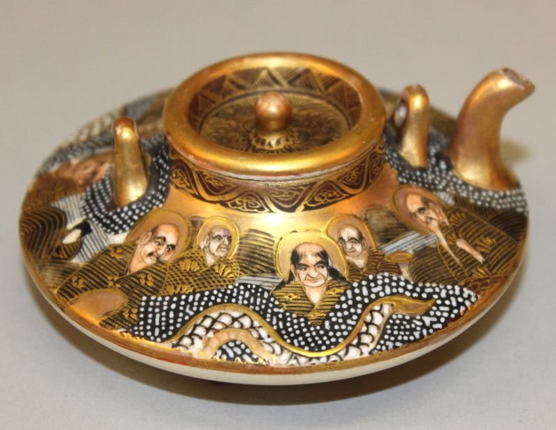 A SIGNED JAPANESE SATSUMA EARTHENWARE KETTLE & COVER,: A SIGNED JAPANESE SATSUMA EARTHENWARE KETTLE & COVER, circa 1900, decorated with sennin in the company of a dragon, 3.5in diameter & 1.6in high.