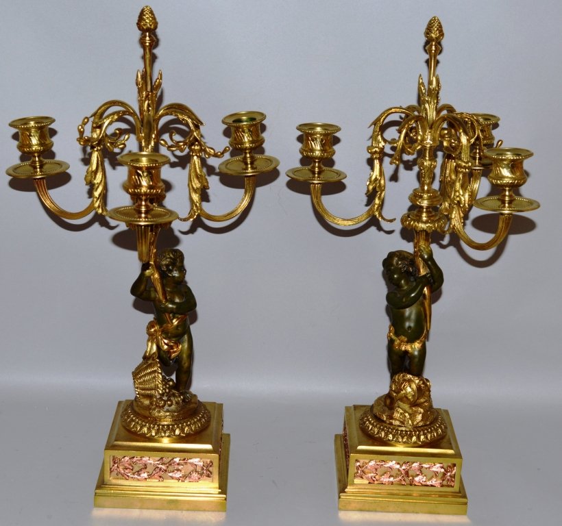 A PAIR OF 19TH CENTURY FRENCH BRONZE AND GILT METAL: A PAIR OF 19TH CENTURY FRENCH BRONZE AND GILT METAL THREE LIGHT CANDELABRA formed as young bronze cupids holding aloft three scrolling branches and supported on square bases. 18.5ins high.