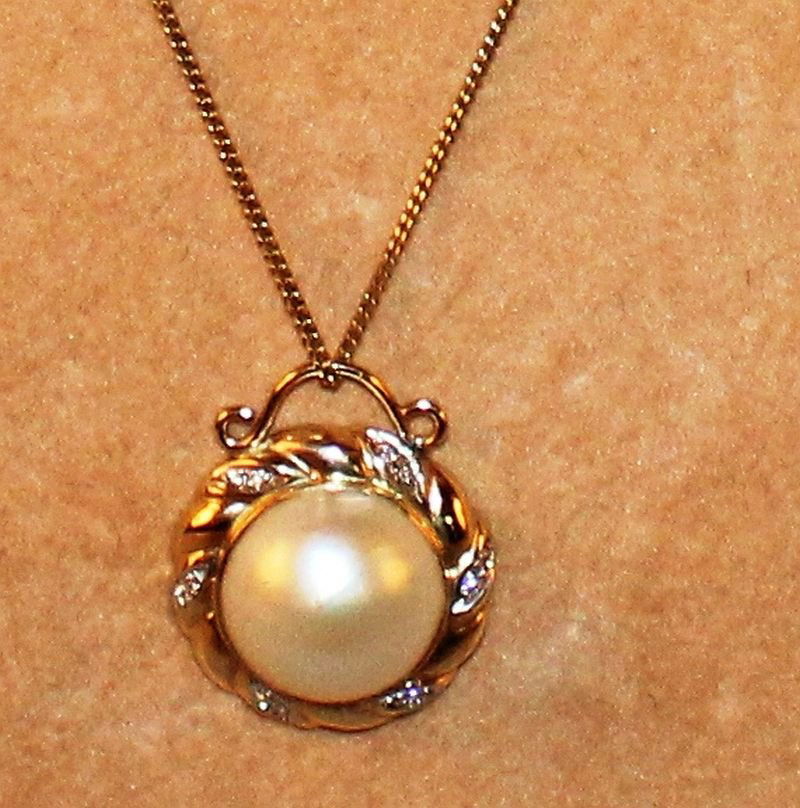 A GOLD, PEARL AND DIAMOND SET PENDANT on a gold chain.: A GOLD, PEARL AND DIAMOND SET PENDANT on a gold chain.