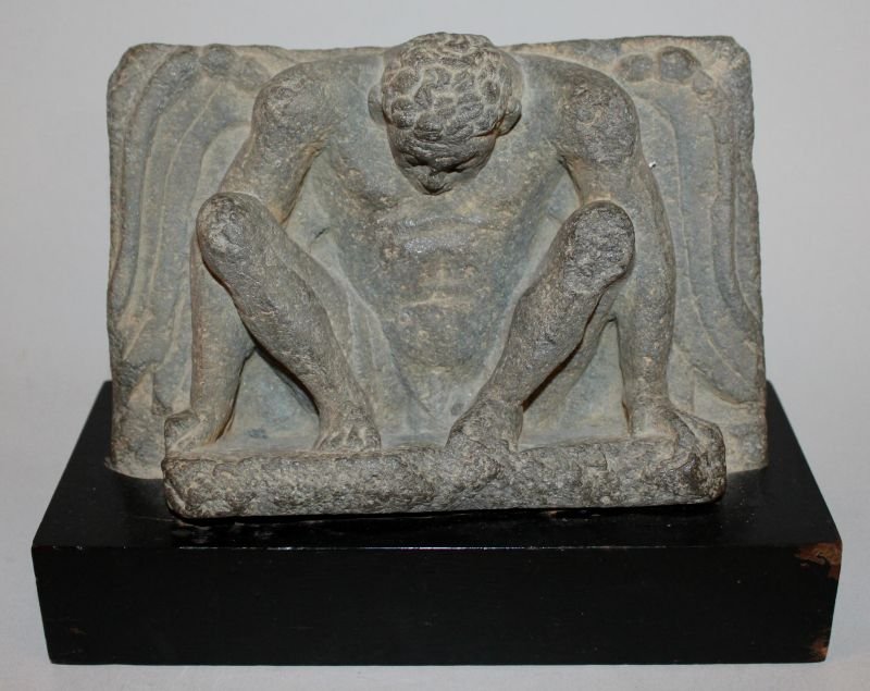 AN UNUSUAL GANDHARA SCHIST CARVING OF A HELLENISTIC: AN UNUSUAL GANDHARA SCHIST CARVING OF A HELLENISTIC WINGED MAN, 2nd/3rd Century, mounted on a wood base, the figure with spread wings and downcast head, the base 8in x 3.4in, the figure itself 7in wid