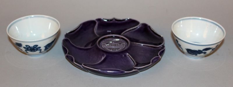 A CHINESE PURPLE PORCELAIN LOTUS DISH, centred by a: A CHINESE PURPLE PORCELAIN LOTUS DISH, centred by a Shou symbol, the base with a Qianlong seal mark, 6.2in diameter; together with a pair of blue and white teabowls bearing Yongzheng marks, each 3.1in