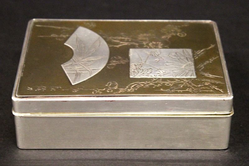 A GOOD QUALITY JAPANESE MEIJI PERIOD MIXED METAL BOX &: A GOOD QUALITY JAPANESE MEIJI PERIOD MIXED METAL BOX & COVER, with a wood lining, the top surface onlaid with silver-metal floral panels reserved on a blossom-incised copper alloy ground, the sides an