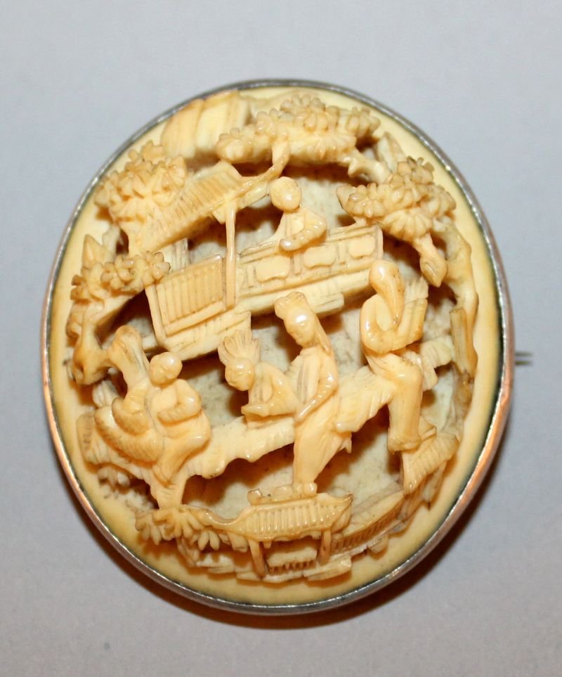 TWO 19TH CENTURY CHINESE CANTON IVORY OVAL PLAQUES, one: TWO 19TH CENTURY CHINESE CANTON IVORY OVAL PLAQUES, one mounted as a brooch, each carved in deep relief with a scene of diminutive figures in a garden terrace setting, 2.2in x 1.6in & 1.9in x 1.6in. (