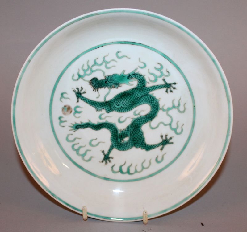 A CHINESE GREEN ENAMELLED DRAGON SAUCER DISH, the: A CHINESE GREEN ENAMELLED DRAGON SAUCER DISH, the interior decorated with a sinuous dragon amidst flame scrolls, the exterior sides similarly decorated, the base with a Daoguang seal mark, 7in diamete