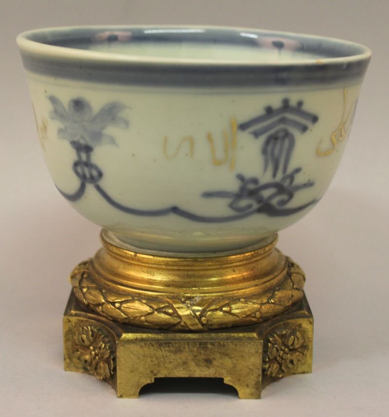 A 17TH/18TH CENTURY ISLAMIC MARKET ORMOLU MOUNTED BLUE: A 17TH/18TH CENTURY ISLAMIC MARKET ORMOLU MOUNTED BLUE & WHITE PORCELAIN BOWL, the interior with an auspicious character, the exterior sides with a formal swag decoration and Islamic characters in gil