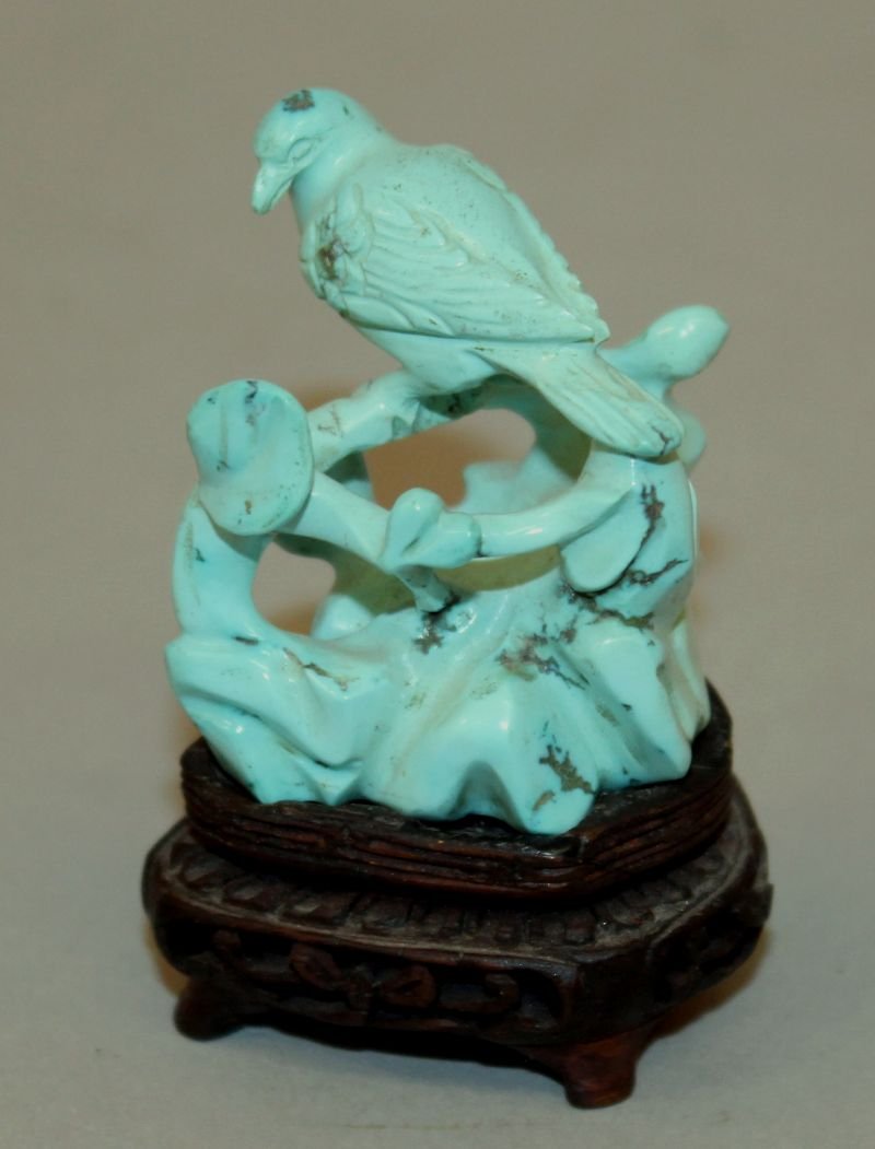 A GOOD EARLY 20TH CENTURY SMALL CHINESE TURQUOISE: A GOOD EARLY 20TH CENTURY SMALL CHINESE TURQUOISE CARVING OF BIRD, perched on rockwork, together with a fitted wood stand, the bird on its stand 2.3in high overall, the bird carving itself 1.6in high.