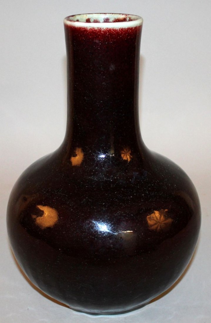 A 19TH/20TH CENTURY CHINESE FLAMBE PORCELAIN BOTTLE: A 19TH/20TH CENTURY CHINESE FLAMBE PORCELAIN BOTTLE VASE, the sides applied with a dark red streaked glaze turning slightly to purple near the foot, the base with a four-character Qianlong mark, 12.8i