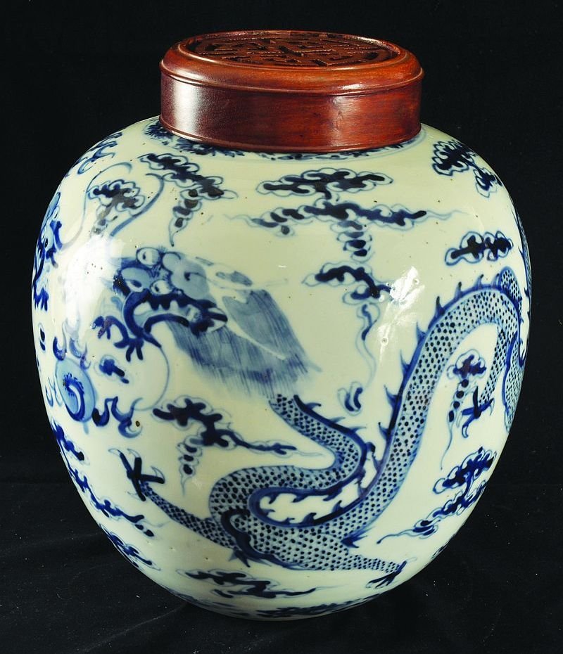 A 19TH CENTURY CHINESE BLUE & WHITE PORCELAIN DRAGON: A 19TH CENTURY CHINESE BLUE & WHITE PORCELAIN DRAGON JAR, with a hardwood cover, the cover pierced and carved with a shou symbol, 10.8in high overall with cover. (2)