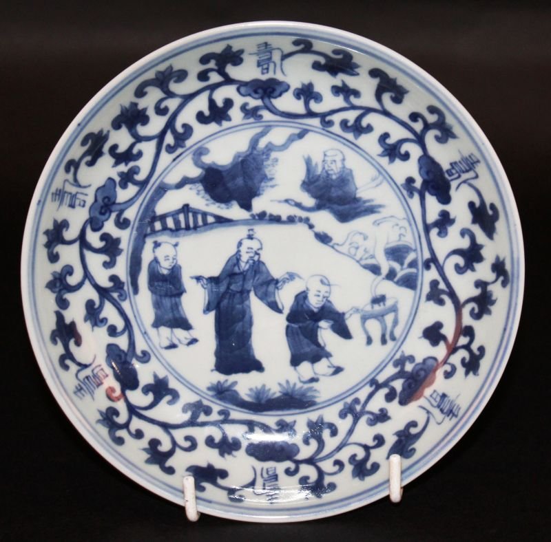 A CHINESE BLUE & WHITE PORCELAIN DISH, decorated to its: A CHINESE BLUE & WHITE PORCELAIN DISH, decorated to its centre with a scene of a sage and attendants in a fenced garden setting and with a phoenix-borne Immortal above waves, the base with a six-chara