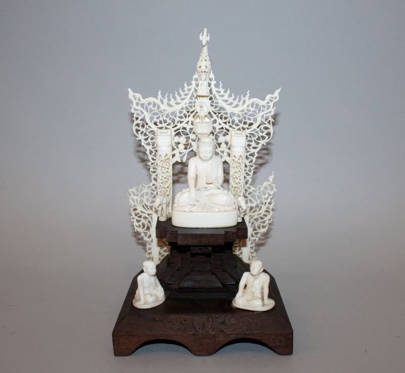 A 19TH/20TH CENTURY THAI IVORY & WOOD SHRINE, centred: A 19TH/20TH CENTURY THAI IVORY & WOOD SHRINE, centred by a good quality ivory carving of Buddha raised on a wood plinth and flanked by two ivory elephants, behind him an elaborate pierced ivory canopy