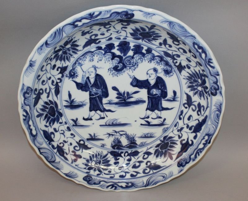 A LARGE GOOD QUALITY CHINESE BLUE & WHITE PORCELAIN: A LARGE GOOD QUALITY CHINESE BLUE & WHITE PORCELAIN CHARGER, with wavy rim, the centre painted with two boys in a garden setting within a scrolling lotus border, 17.1in diameter.