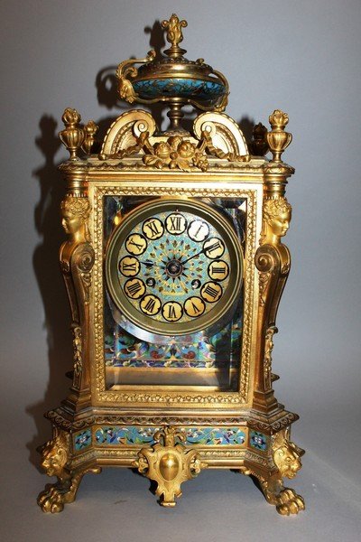 A GOOD 19TH CENTURY FRENCH CHAMPLEVE ENAMEL, ORMOLU AND: A GOOD 19TH CENTURY FRENCH CHAMPLEVE ENAMEL, ORMOLU AND ONYX CLOCK with eight day movement striking on a bell, with urn finial, caryatid figures, on claw feet. 18.5ins high.