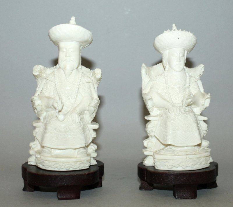 A PAIR OF 20TH CENTURY CHINESE IVORY-LIKE MODELS OF AN: A PAIR OF 20TH CENTURY CHINESE IVORY-LIKE MODELS OF AN EMPEROR & AN EMPRESS, together with wood stands, 6.1in high overall. John Nicholsons Auctioneers do not ship items containing ivory to the USA or