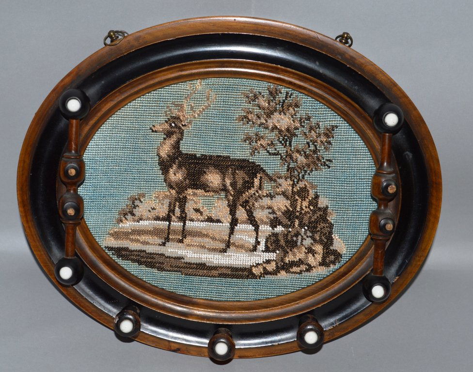 A VICTORIAN WALNUT OVAL COAT RACK, with beadwork panel: A VICTORIAN WALNUT OVAL COAT RACK, with beadwork panel depicting a stag by a tree.1ft 1ins wide.
