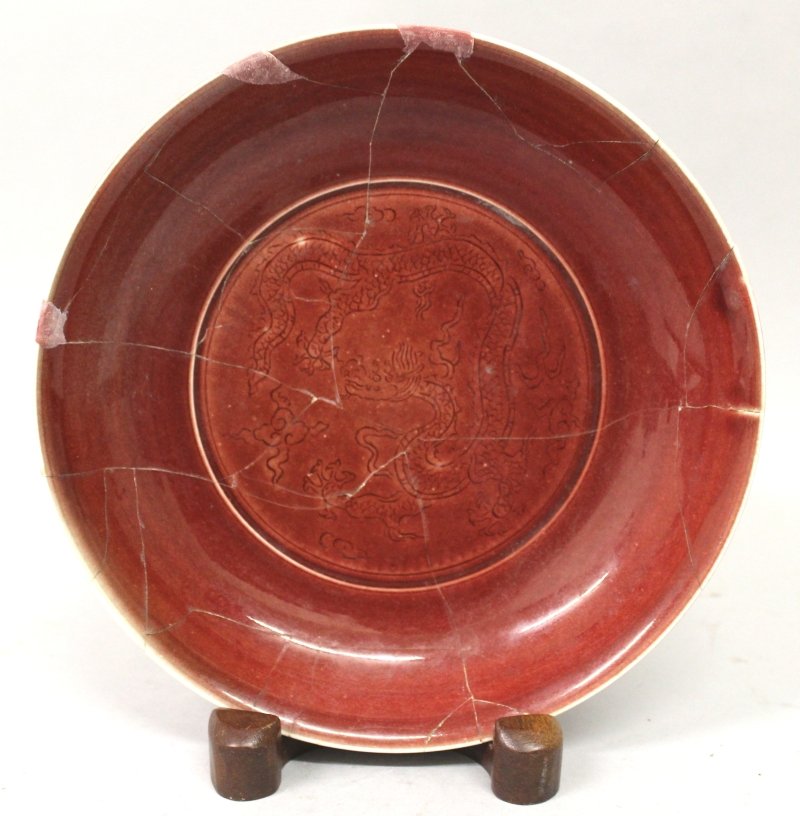 A CHINESE OX BLOOD GLAZED PORCELAIN SAUCER DISH,: A CHINESE OX BLOOD GLAZED PORCELAIN SAUCER DISH, decorated to its centre with a sinuous dragon amidst cloud scrolls, the base with a six-character Xuande mark, 8.4in diameter. £150-250