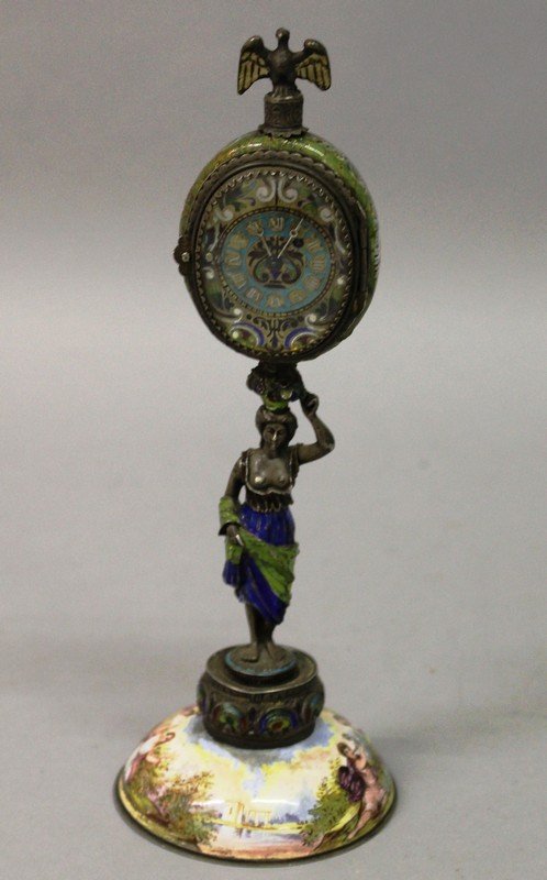 A SUPERB SILVER AND VIENNA ENAMEL CLOCK with watch: A SUPERB SILVER AND VIENNA ENAMEL CLOCK with watch movement by Chapuy in an oval case with painted Vienna enamel back, supported by a silver and enamel figure of a young lady and supported on a silver