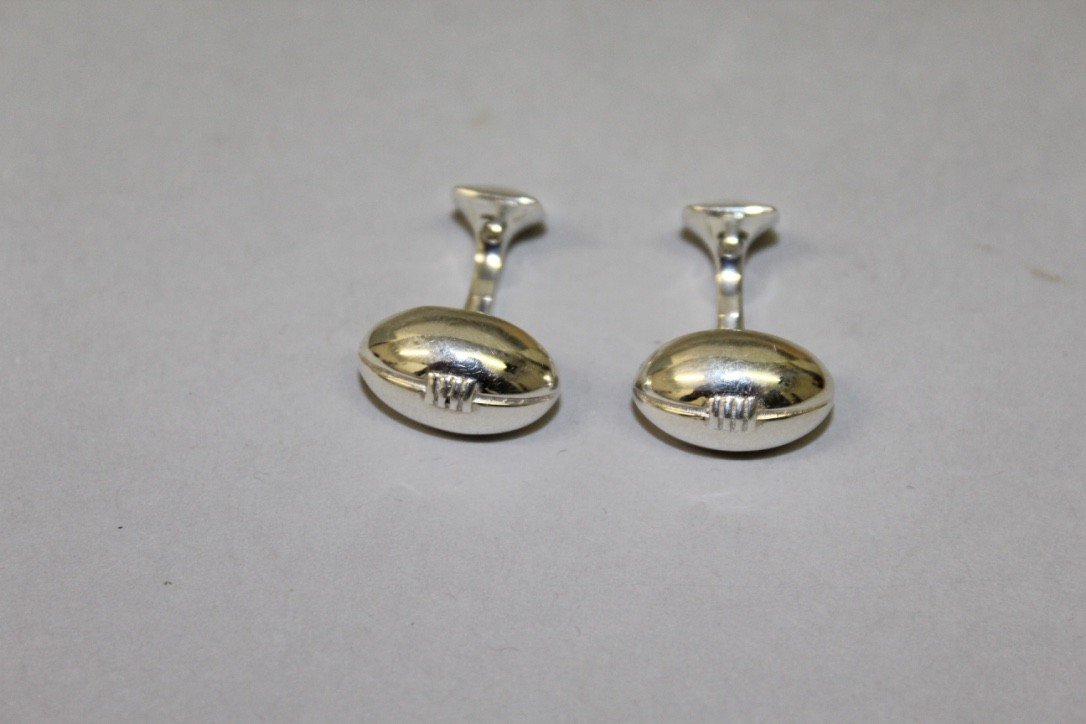 A pair of hallmarked sterling silver cufflinks in the: A pair of hallmarked sterling silver cufflinks in the form of rugby balls.