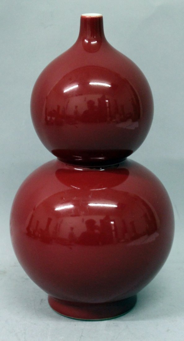 A CHINESE SANG-DE-BOEUF DOUBLE GOURD PORCELAIN VASE,: A CHINESE SANG-DE-BOEUF DOUBLE GOURD PORCELAIN VASE, the side applied with an even glaze, the base with a Qianlong seal mark, 9.5in high.