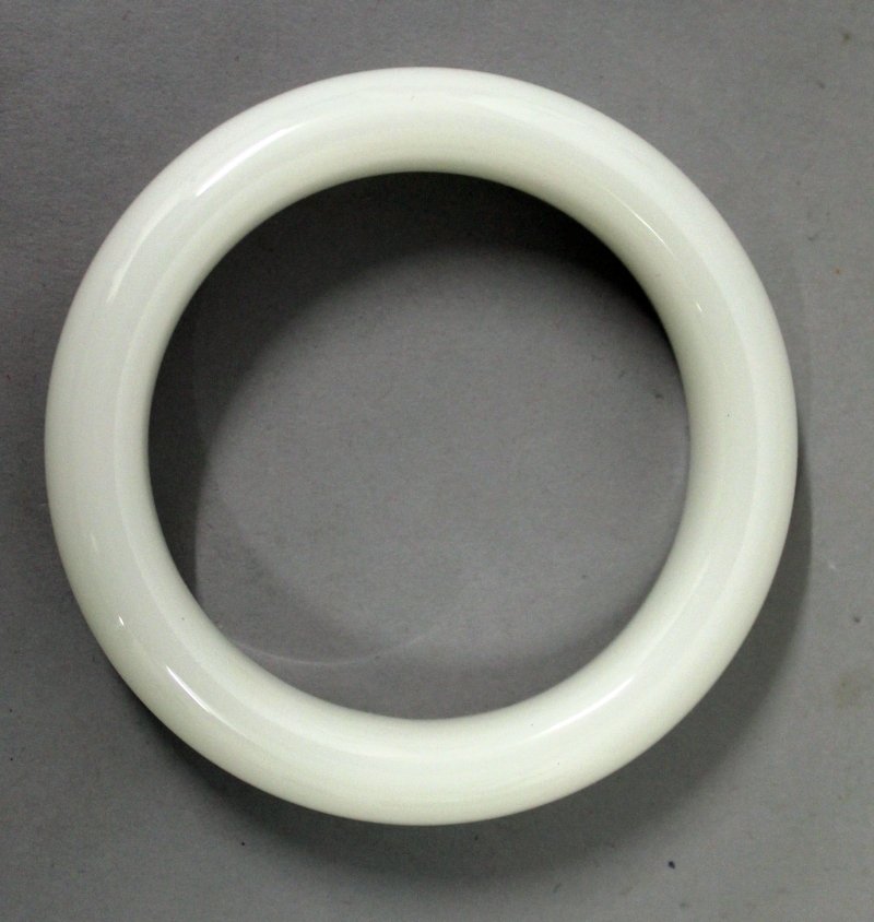 A CHINESE WHITE JADE-LIKE BANGLE, 3.2in diameter, the (1 of 2)