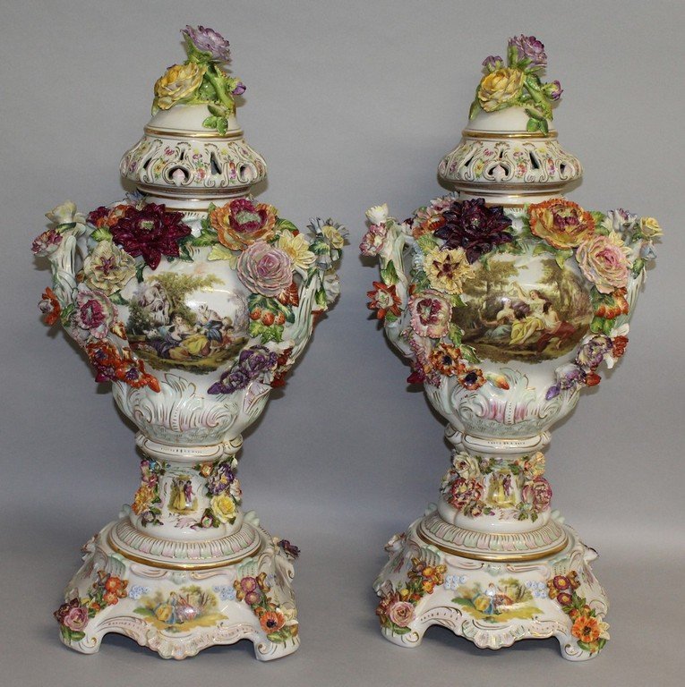 A LARGE PAIR OF "DRESDEN" FLOWER ENCRUSTED TWO HANDLED: A LARGE PAIR OF "DRESDEN" FLOWER ENCRUSTED TWO HANDLED URN SHAPED VASES, COVERS AND STANDS painted with panels of young lovers and flowers. 2ft 6ins high.
