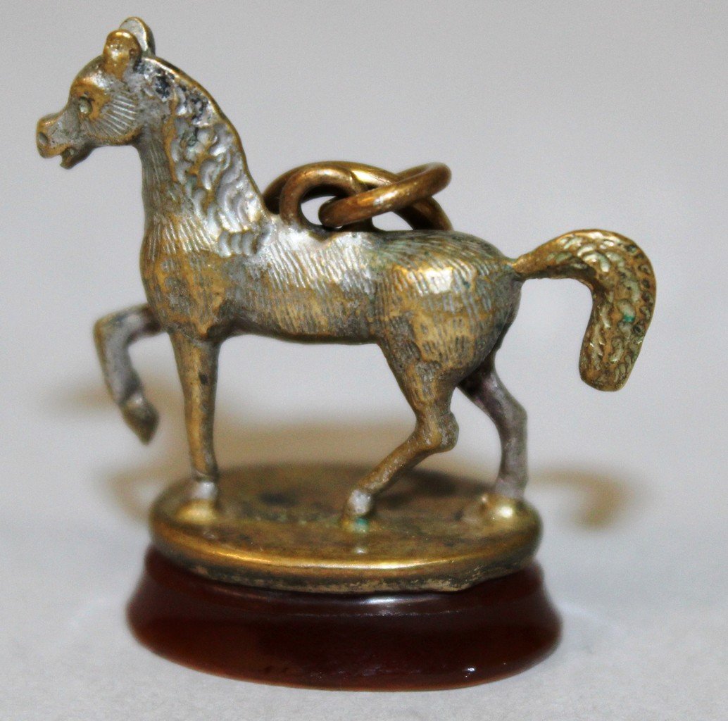 A GILT METAL SEAL AS A HORSE with oval cornelian: A GILT METAL SEAL AS A HORSE with oval cornelian intaglio with an incised horse.