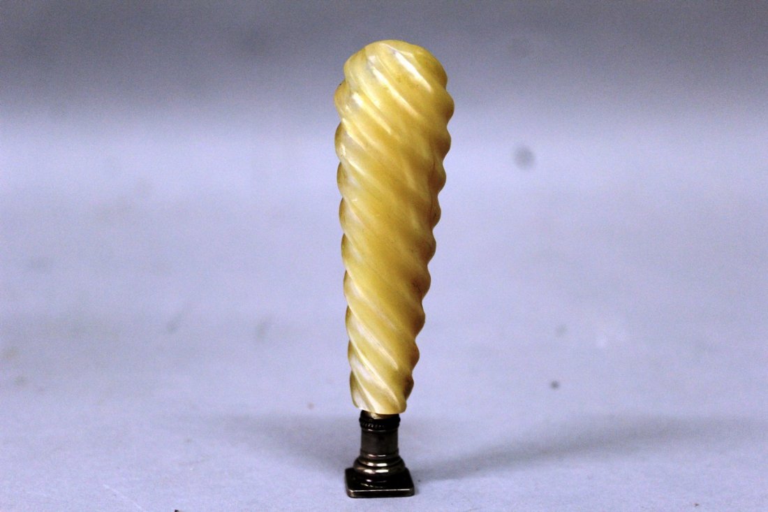 A MOTHER-OF-PEARL HANDLED DESK SEAL, the rounded: A MOTHER-OF-PEARL HANDLED DESK SEAL, the rounded rectangular intaglio with incised crest and motto, with bead borders to the white metal mounts and spiral fluted grip. 9