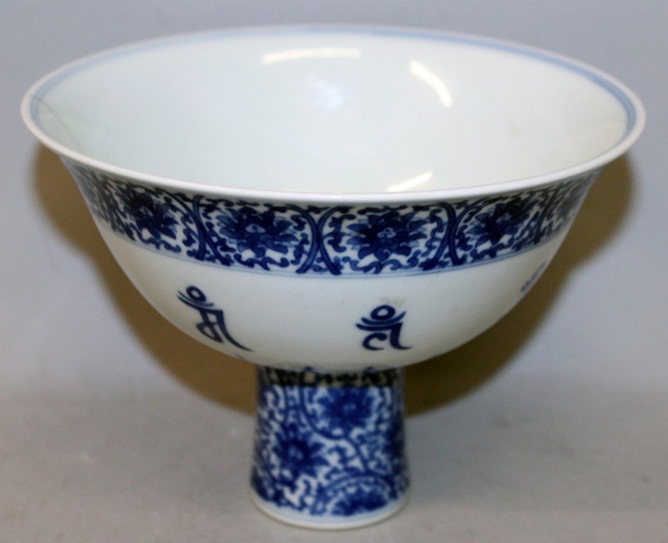 A CHINESE BLUE & WHITE PORCELAIN STEM BOWL, the: A CHINESE BLUE & WHITE PORCELAIN STEM BOWL, the interior centre and sides decorated with Mongolian script characters, the foot and exterior rim with formal scrolling lotus, the inside of the foot with