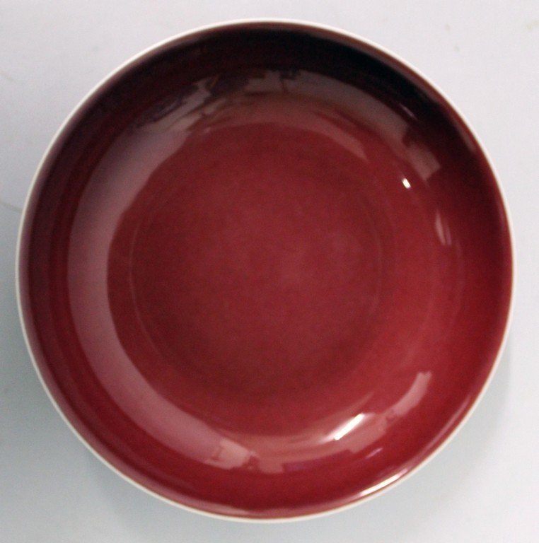 A CHINESE SANG-DE-BOEUF PORCELAIN SAUCER DISH, applied: A CHINESE SANG-DE-BOEUF PORCELAIN SAUCER DISH, applied with an even glaze pooling slightly at the foot, the base with a six-character Yongzheng mark, 7.1in diameter.