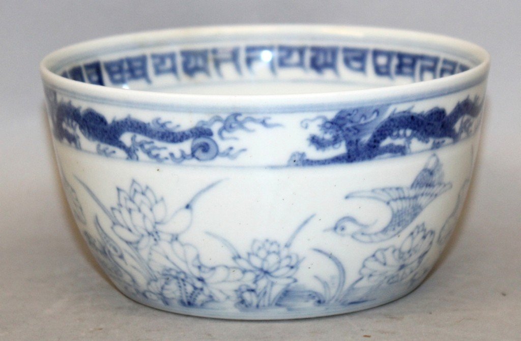 A CHINESE BLUE & WHITE PORCELAIN BOWL, the sides: A CHINESE BLUE & WHITE PORCELAIN BOWL, the sides decorated beneath a dragon border with a continuous scene of ducks and lotus, the base with a six-character Yongzheng mark, 4.9in diameter & 2.6in high