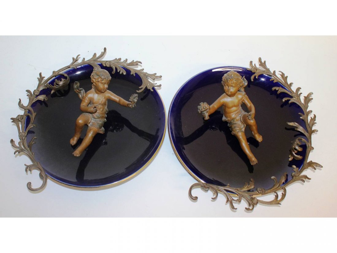 A pair of blue porcelain circular plaques with ormolu: A pair of blue porcelain circular plaques with ormolu cupid and mount. 10ins diameter.