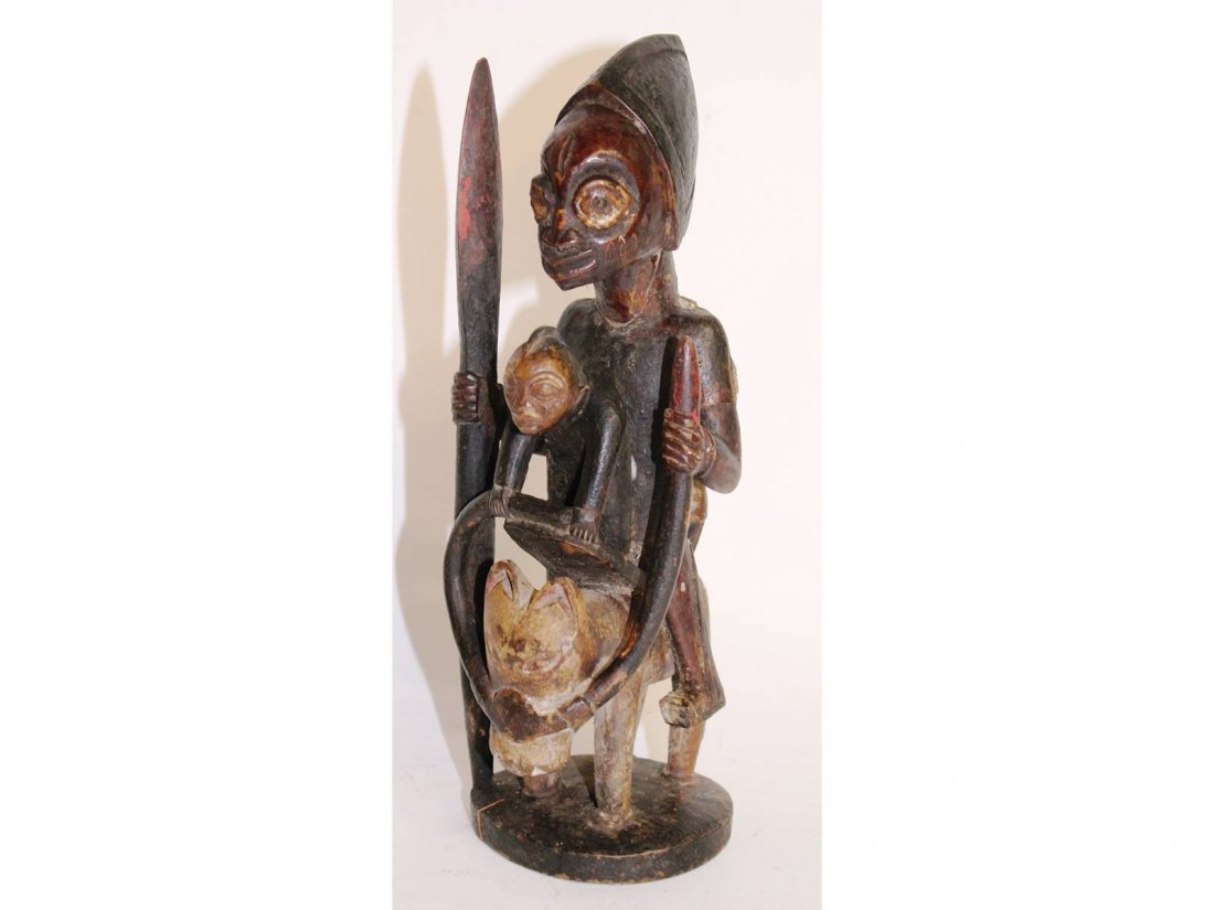 A carved wood tribal figure with young boy riding a: A carved wood tribal figure with young boy riding a camel. 10ins high.