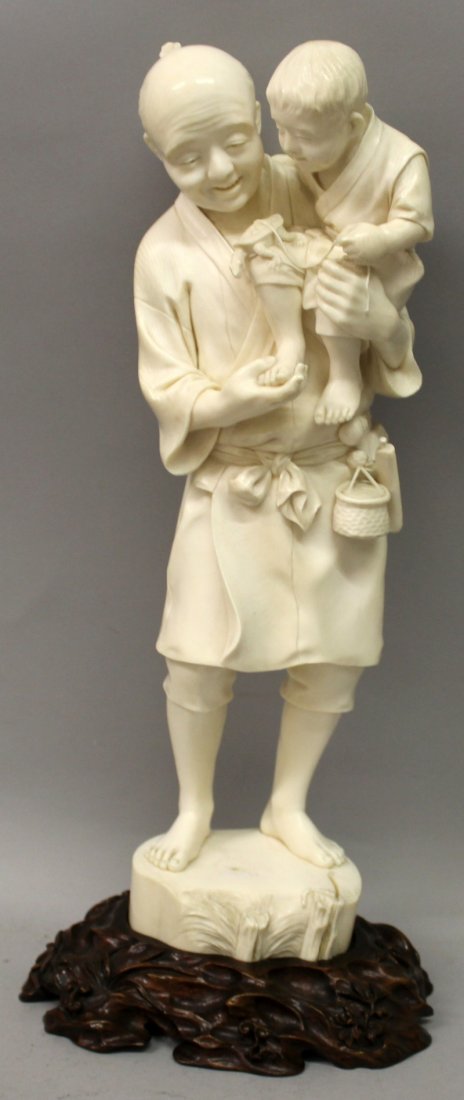A LARGE FINE QUALITY SIGNED JAPANESE MEIJI PERIOD TOKYO: A LARGE FINE QUALITY SIGNED JAPANESE MEIJI PERIOD TOKYO SCHOOL IVORY OKIMONO, together with a good quality carved and fitted wood stand, the ivory carved in the form of a man holding his son in his ar