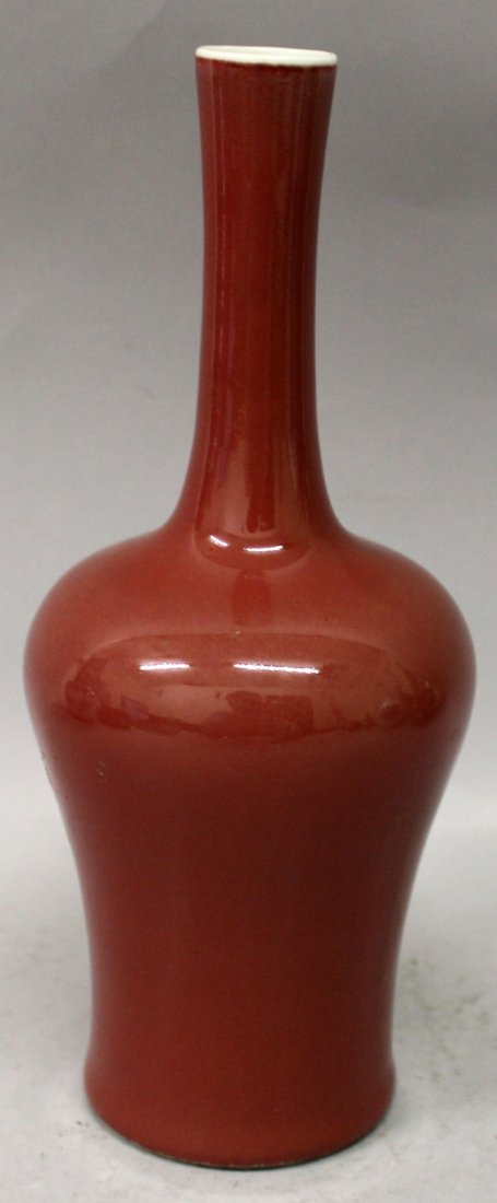 A CHINESE SANG-DE-BOEUF PORCELAIN VASE, applied with an: A CHINESE SANG-DE-BOEUF PORCELAIN VASE, applied with an even glaze, the base with a four-character Kangxi mark, 9.75in high.