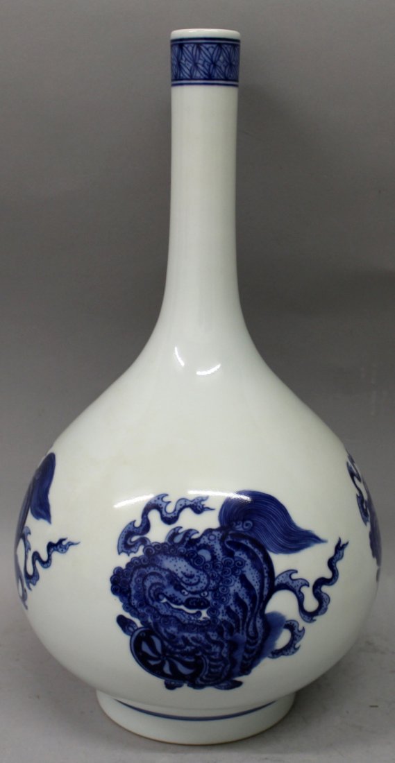 A CHINESE BLUE & WHITE PORCELAIN BOTTLE VASE, decorated: A CHINESE BLUE & WHITE PORCELAIN BOTTLE VASE, decorated with buddhistic lions playing with ribboned and brocaded balls, the base with a Qianlong seal mark, 14.2in high.