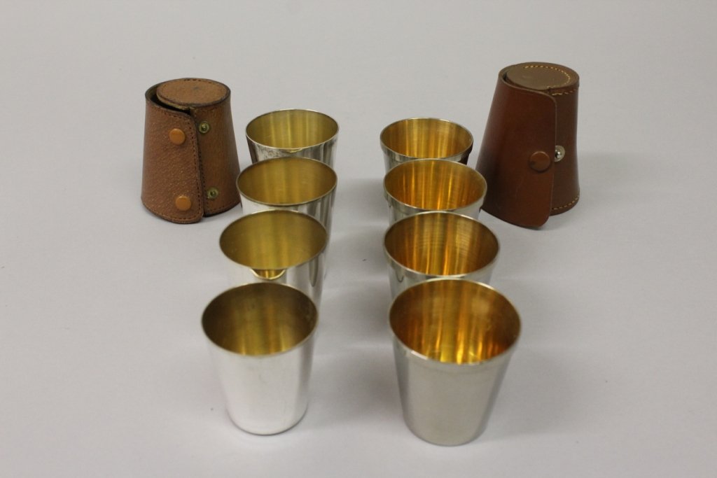 A SET OF FOUR GILDED BEAKERS in a leather case and a: A SET OF FOUR GILDED BEAKERS in a leather case and a similar set of three (2).
