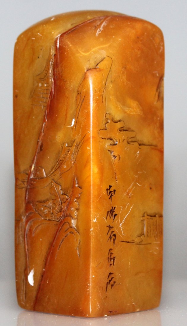 A CHINESE STONE SEAL, of amber tone, decorated in low: A CHINESE STONE SEAL, of amber tone, decorated in low relief with calligraphy and with sages in a mountainous landscape, 3.4in high & 1.25in square at base.