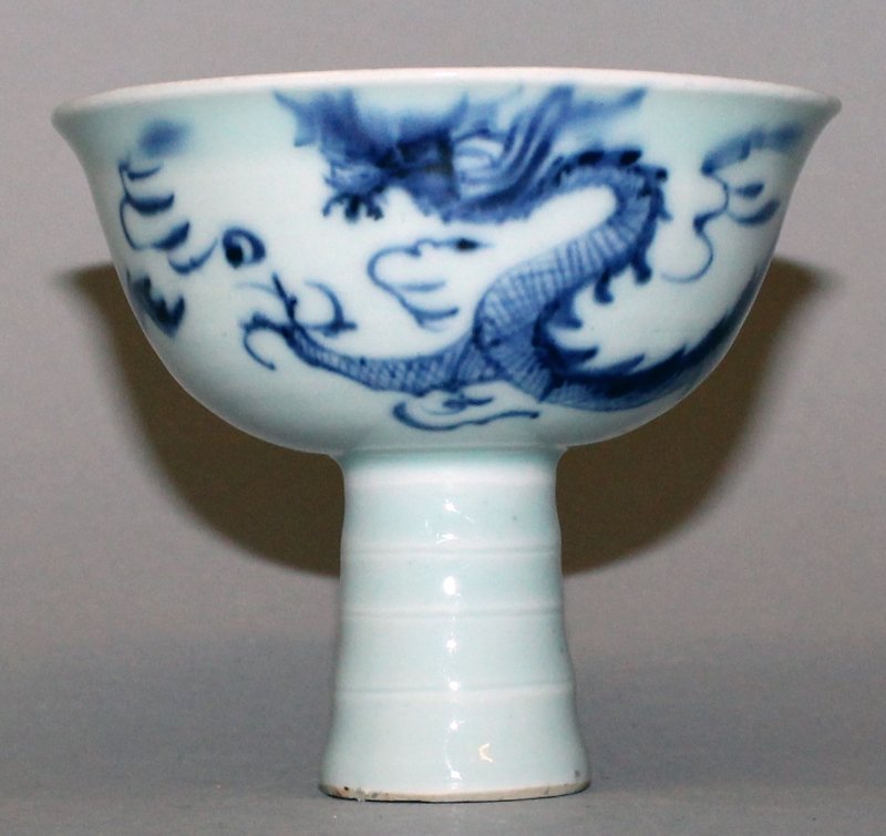A CHINESE MING STYLE BLUE & WHITE PORCELAIN STEM BOWL,: A CHINESE MING STYLE BLUE & WHITE PORCELAIN STEM BOWL, the sides decorated with a sinuous dragon pursuing a flaming pearl, 3.9in diameter at rim & 3.5in high.