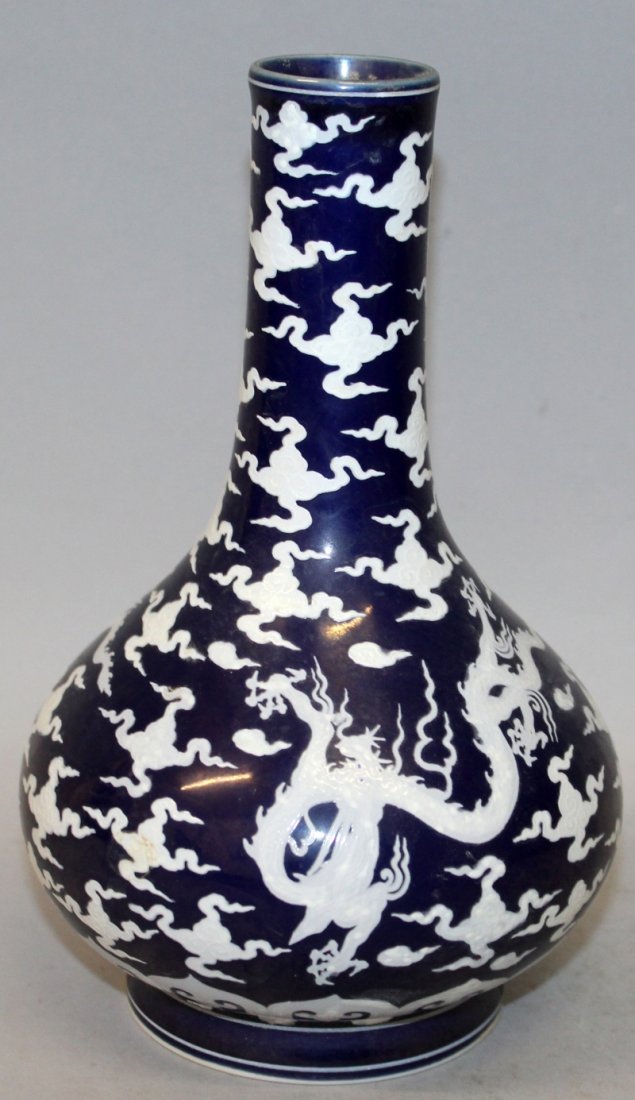 A CHINESE BLUE GROUND PORCELAIN VASE, decorated in: A CHINESE BLUE GROUND PORCELAIN VASE, decorated in white with dragons amidst cloud scrolls, the base with a six-character Chenghua mark, 7.5in high.