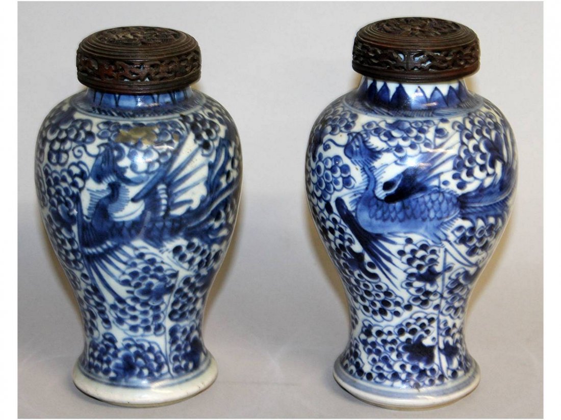 A PAIR OF CHINESE KANGXI PERIOD BLUE & WHITE PORCELAIN: A PAIR OF CHINESE KANGXI PERIOD BLUE & WHITE PORCELAIN VASES, with a pair of pierced hardwood covers, each vase painted with a phoenix reserved on a ground of dense peony. 7.4in & 7.2in high overall w