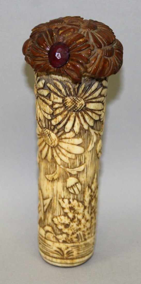 AN EARLY 20TH CENTURY ORIENTAL CARVED BONE CANE HANDLE,: AN EARLY 20TH CENTURY ORIENTAL CARVED BONE CANE HANDLE, with a carved wood and glass inset pommel, the sides of the bone carved with garden foliage, 5in long.