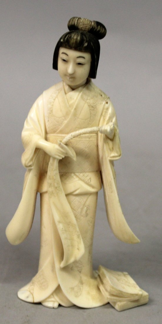 A SIGNED JAPANESE MEIJI PERIOD IVORY OKIMONO OF A YOUNG: A SIGNED JAPANESE MEIJI PERIOD IVORY OKIMONO OF A YOUNG WOMAN, holding a slender bag before her from which she pulls a rope-like object, her coiffured hair stained black, the base with an engraved sig
