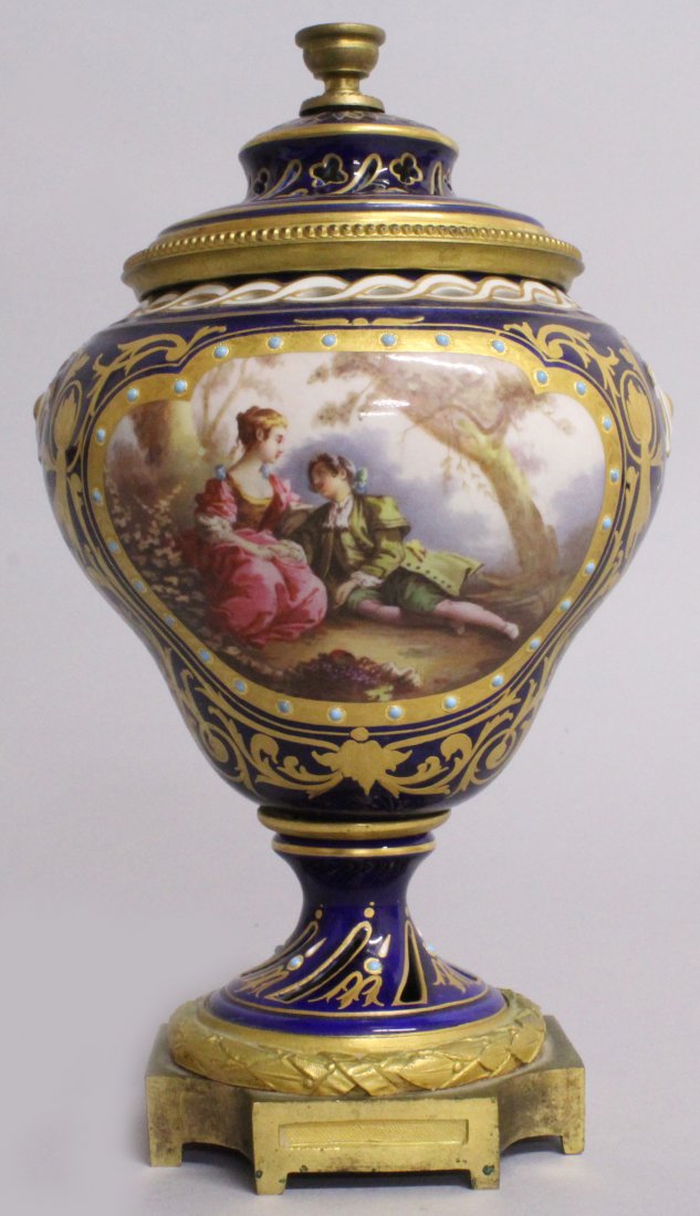 A GOOD 19TH CENTURY SEVRES ORMOLU MOUNTED POTPOURRI: A GOOD 19TH CENTURY SEVRES ORMOLU MOUNTED POTPOURRI VASE AND COVER, rich blue ground edged in gilt and painted with reverse panels of young lovers and flowers. 8ins high.