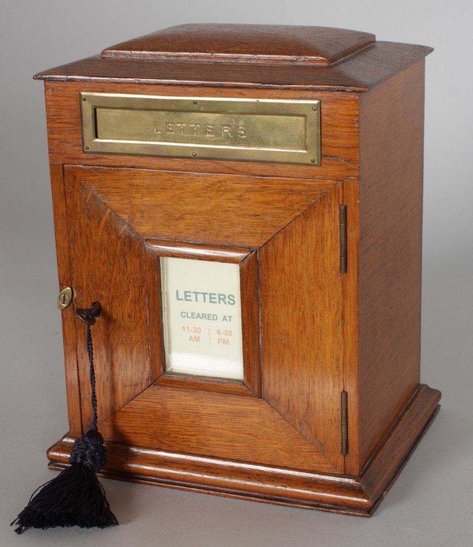 AN EDWARDIAN OAK LETTER BOX, with brass letter flap: AN EDWARDIAN OAK LETTER BOX, with brass letter flap above a door with collection times. 8.5ins wide x 6.5ins deep x 10.5ins high.